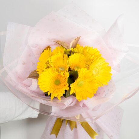 hermoso bouquet ramo de flores gerberas amarillas envuelto en papel de color rosa y moño