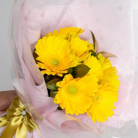 hermoso bouquet ramo de flores gerberas amarillas envuelto en papel de color rosa y moño