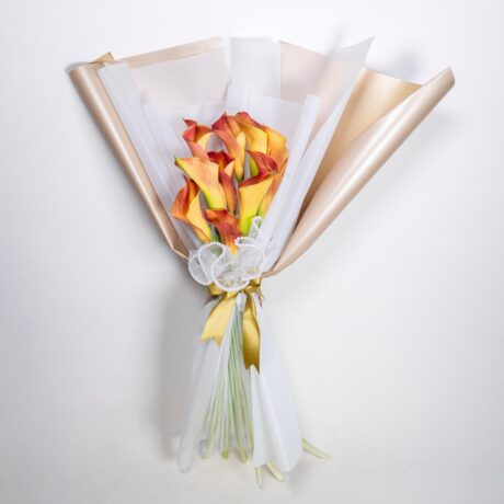 hermoso bouquet de lirios o lacas envuelto en fino papel blanco y dorado