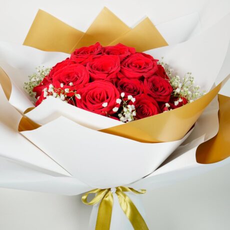Bouquet de rosas ramo de rosas elegantes envueltas en papel elegante blanco y dorado
