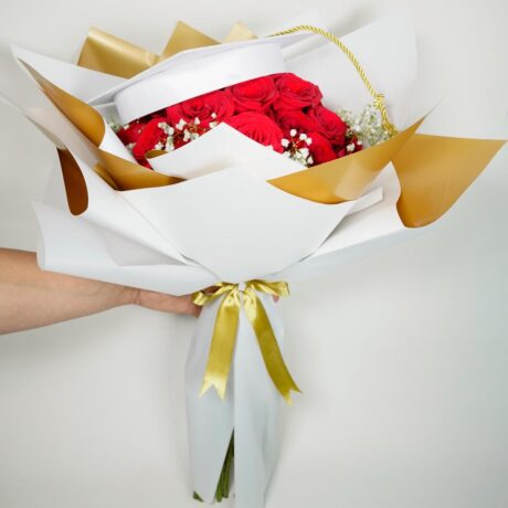Bouquet de rosas ramo de rosas elegantes envueltas en papel elegante blanco y dorado con gorrito de grado