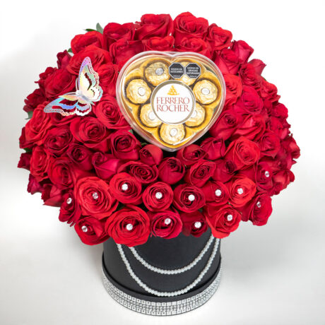 caja de muchas rosas rojas con base tambor negro y una mariposa plateada en la paete superior y chocolates ferrero rocher y cinta de diamantes en la parte inferior