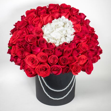 caja de muchas rosas rojas y hortensias con base tambor negro